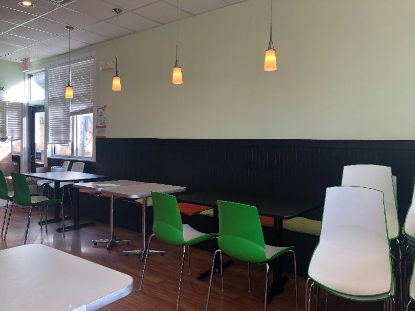The interior of San Maru in March 2021 with tables spaced and green and white chairs stacked. Photo by Alyssa Buckley.