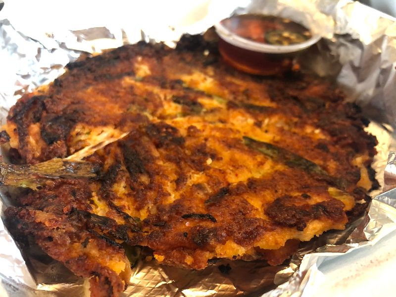 A mung bean pancake sits on a tin foil lined takeout container. Photo by Alyssa Buckley.