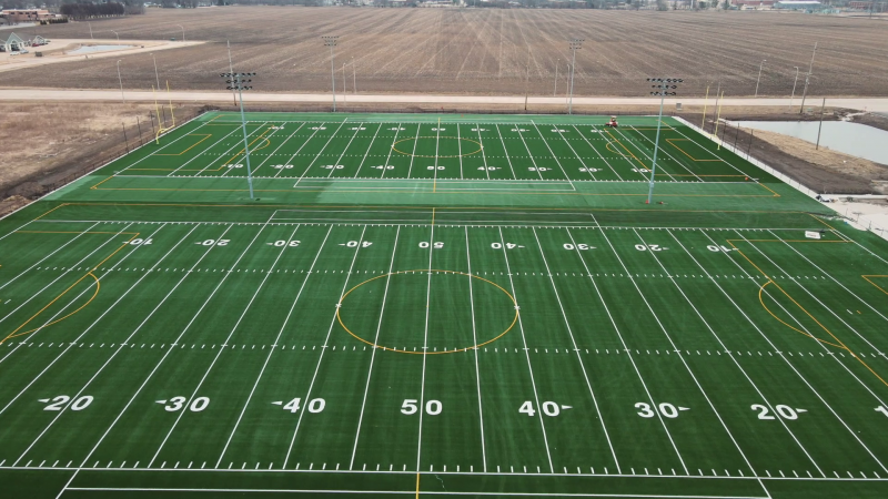 An aerial view of two football fields with green turf and white and yellow lines. The yardlines are numbered in white. Photo by Cole Carpenter.