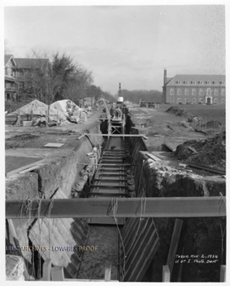 A black and white photo of a construction site, featuring a long trench dug into the ground. Photo from UIUC Archives.