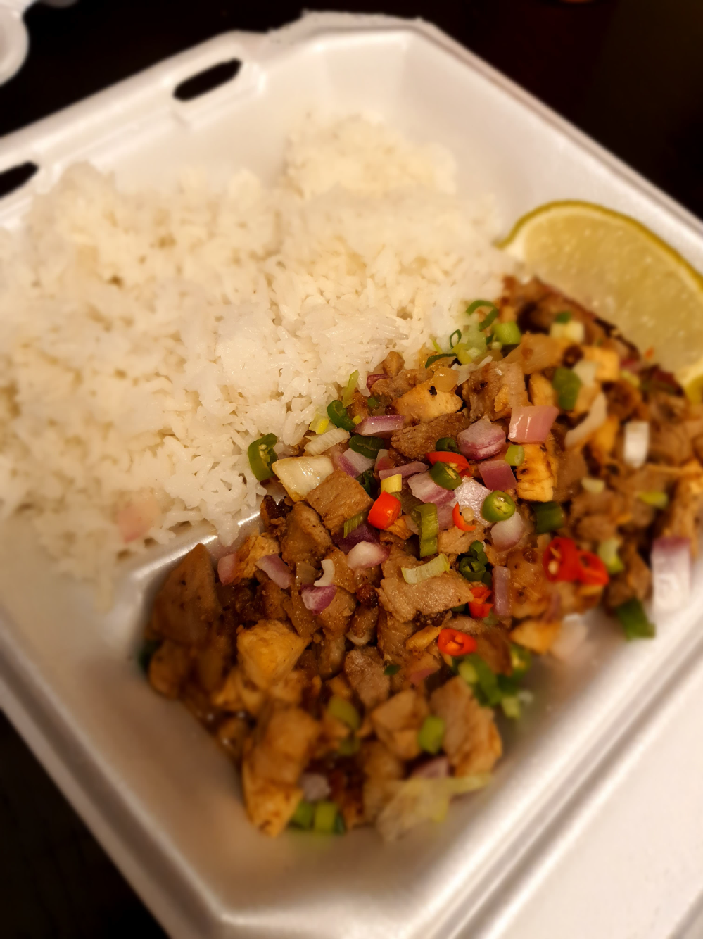 A takeout container has two dividers, half of rice and half of mixed meat diced. Photo by Da Yeon Eom.