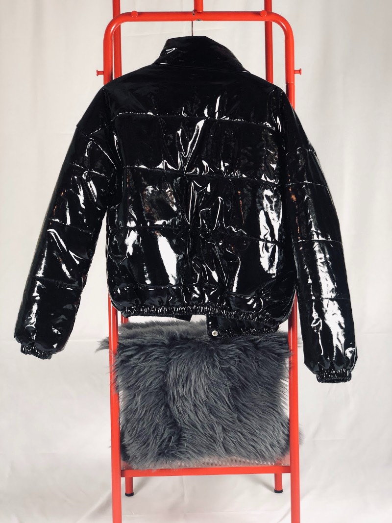 A black, vinyl puffy jacket hangs on a red ladder. There is a gray furry pillow underneath. Photo provided by Karma Trade.