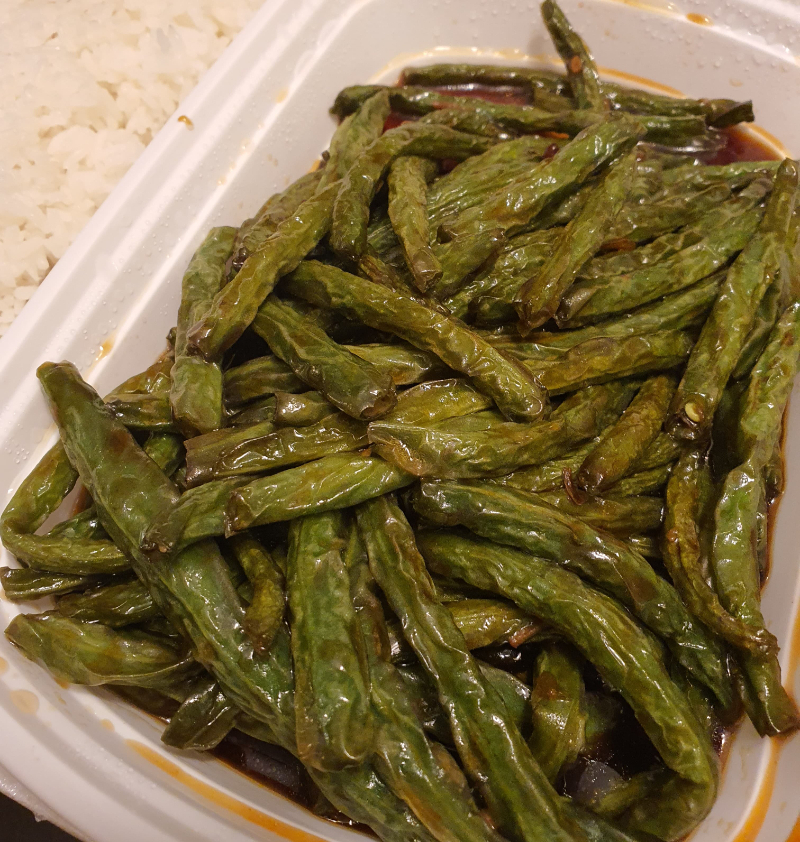 Fried and crispy green beans in a huge heap sit in a plastic takeout container. Photo by Da Yeon Eom.
