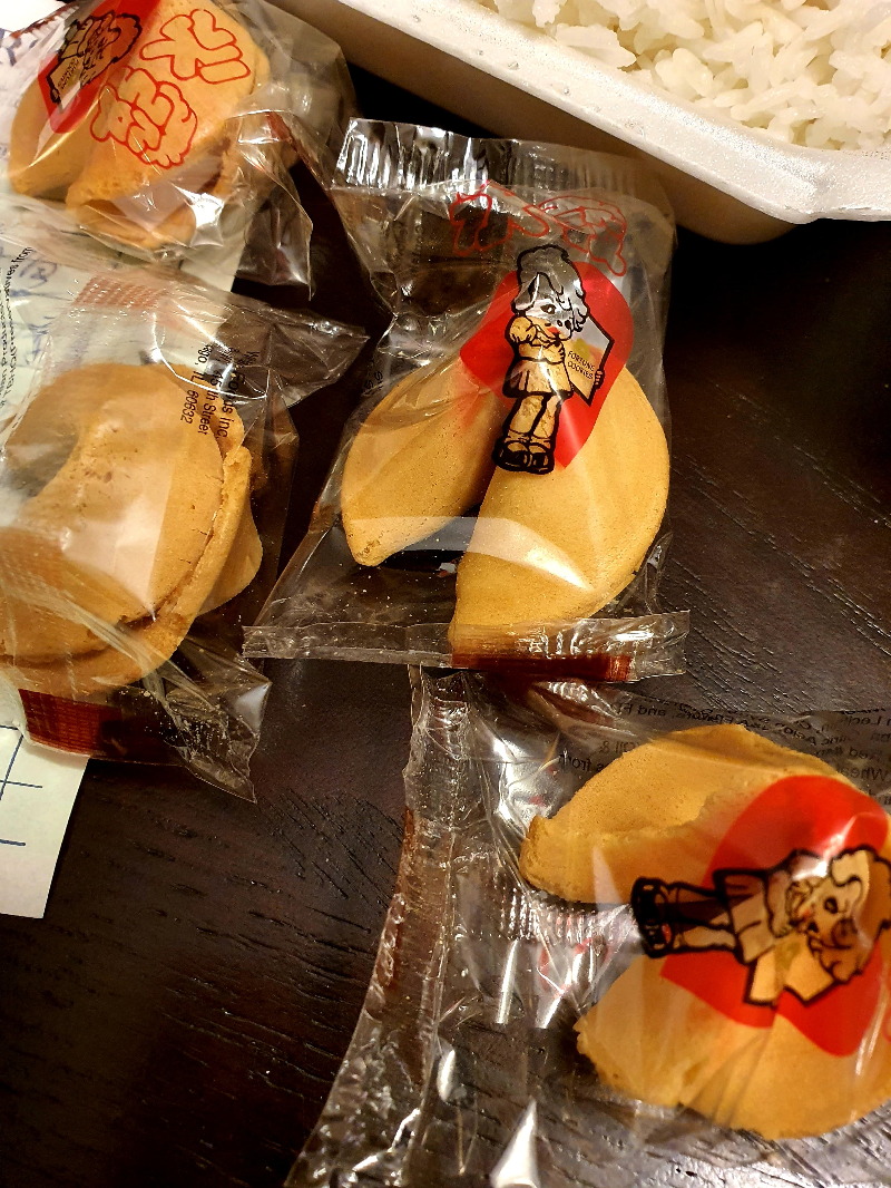 On a wooden table, there are several packaged fortune cookies, unopened. Photo by Da Yeon Eom.