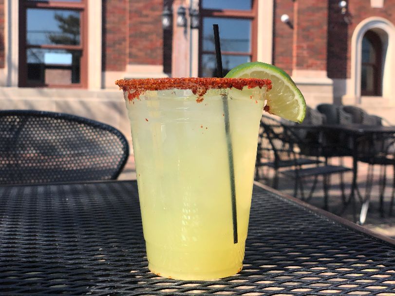 A cucumber lime margarita from Maize at the Station sits on a black wire table on the private patio behind the bricked old train station in Downtown Champaign. Photo by Alyssa Buckley.