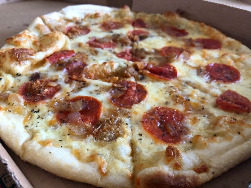 A medium pizza with pepperoni and white sauce is dusted with bread crumbs and a few caramelized onions. Photo by Alyssa Buckley.