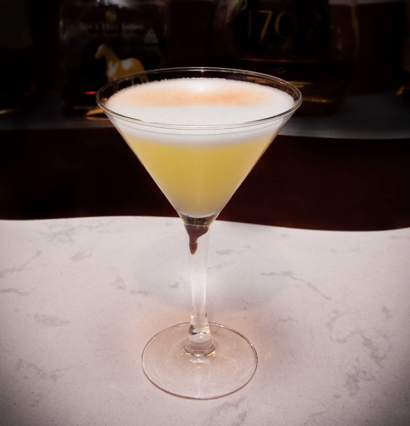 A wedge shaped martini glass is filled with yellow liquid and a white froth. Photo provided by Hamilton Walker's. 
