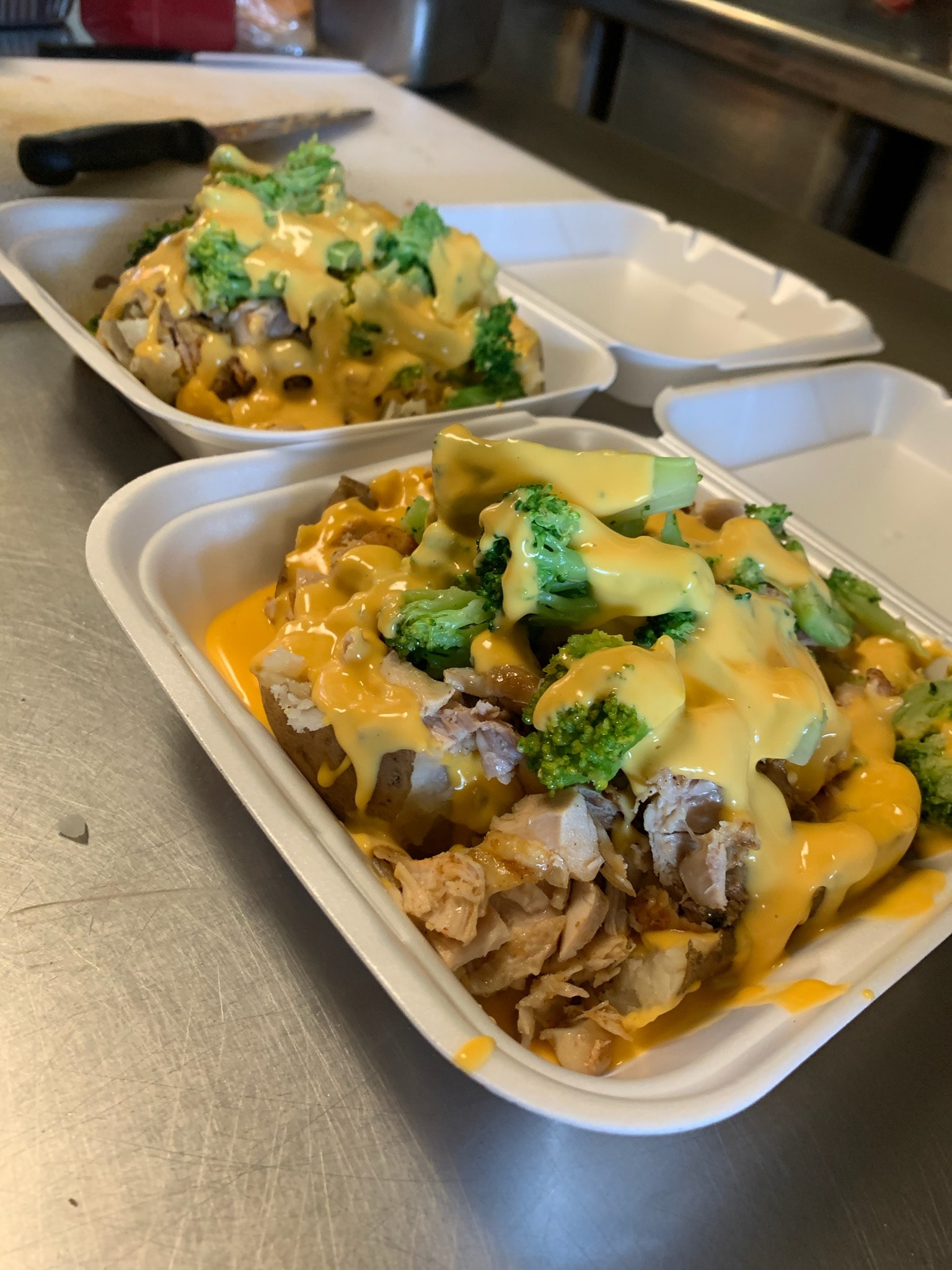 An entire container is full of baked potato covered with cheese, broccoli, and smoked chicken. Photo from Dis N' Dat BBQ Facebook page.