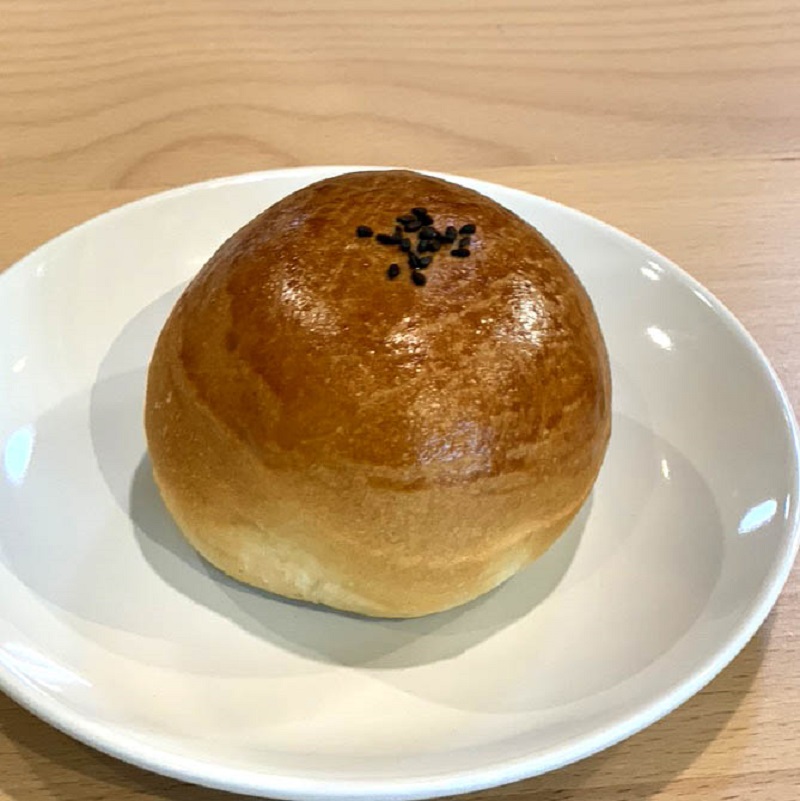 A round an pan sits on a white plate on a light wooden table. Photo by Suzu's Bakery.