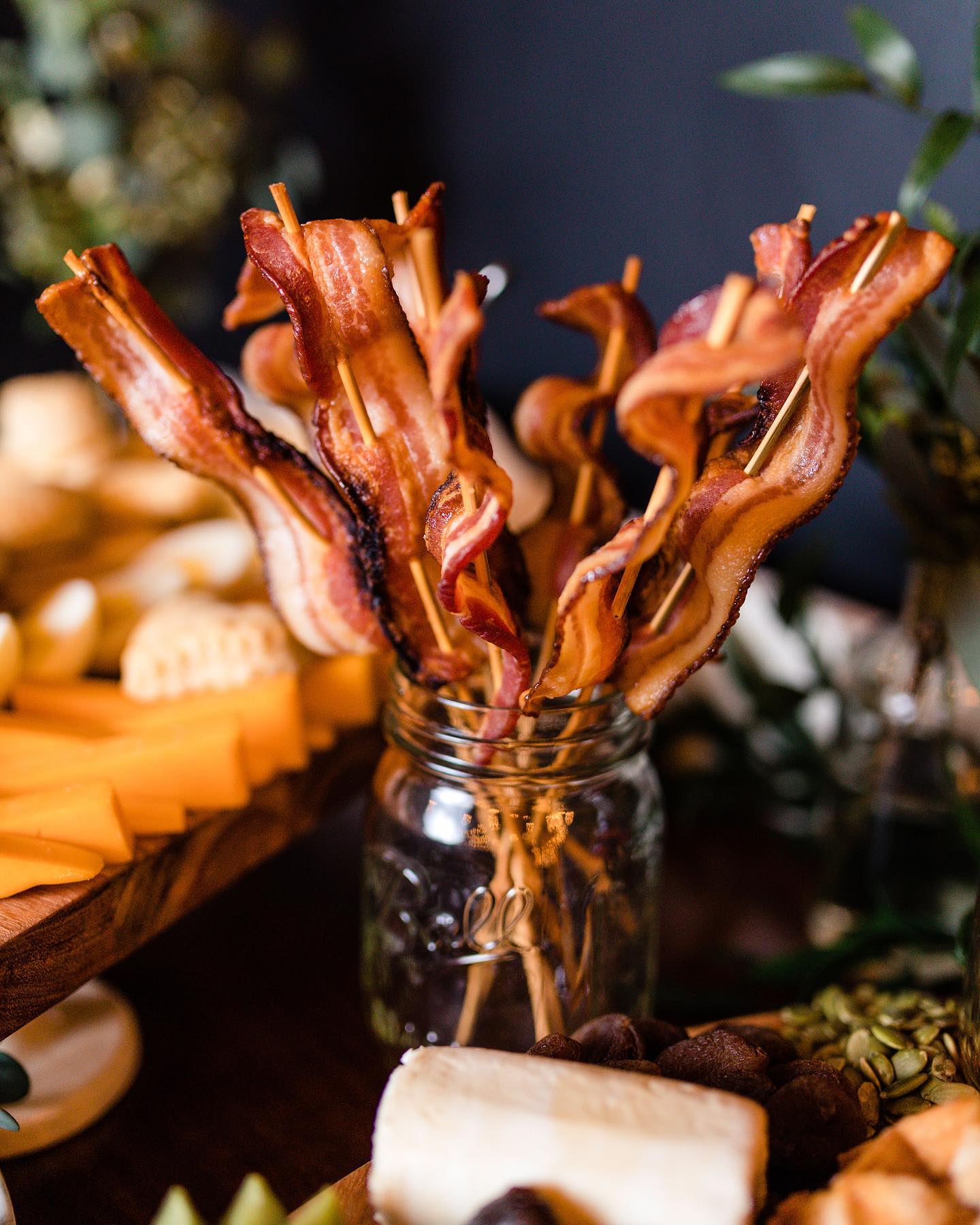 A mason jar is filled with curved bacon on wooden sticks. Photo from Crafted and Carved's Facebook page.