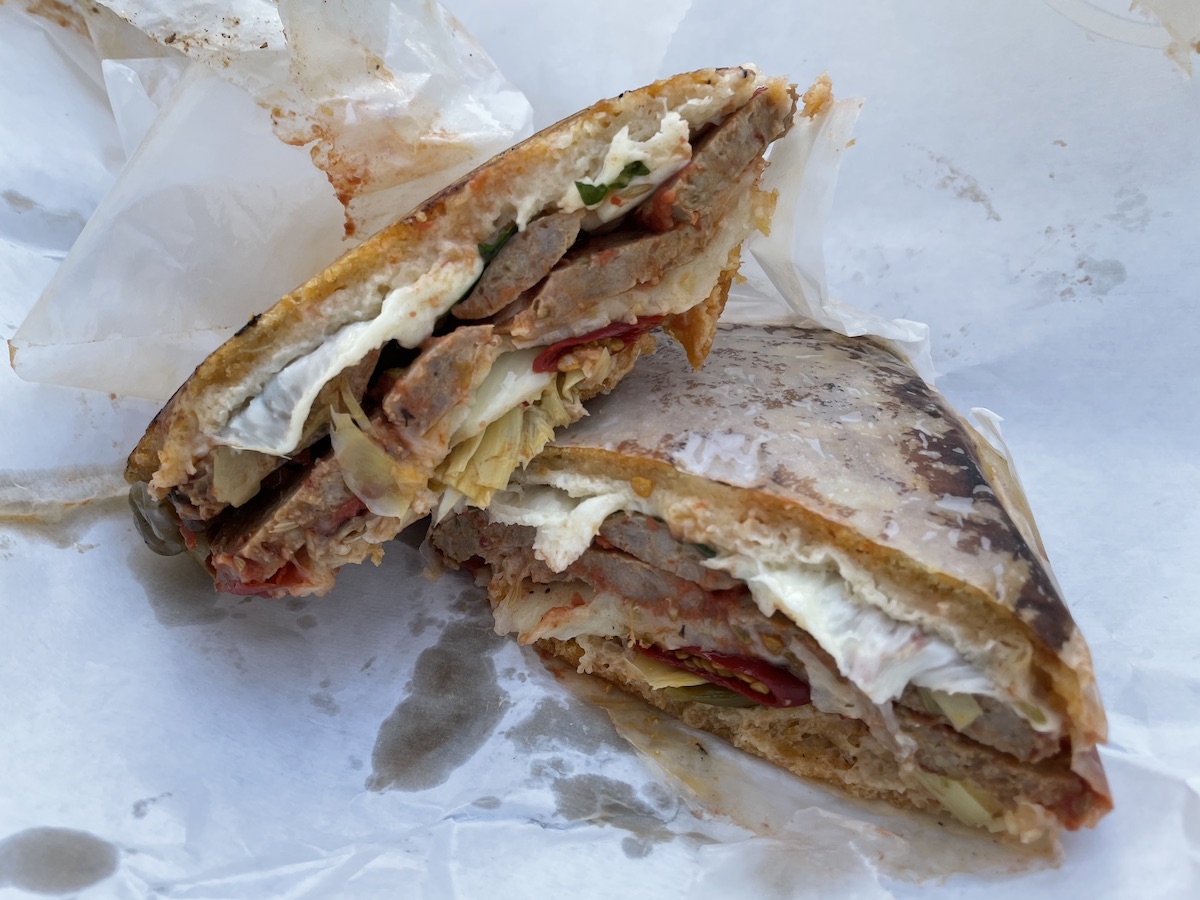 A photo of the Hot Sicilian Sausage Sandwich form Baldoratta's on white parchment paper. Photo by Anthony Erlinger.