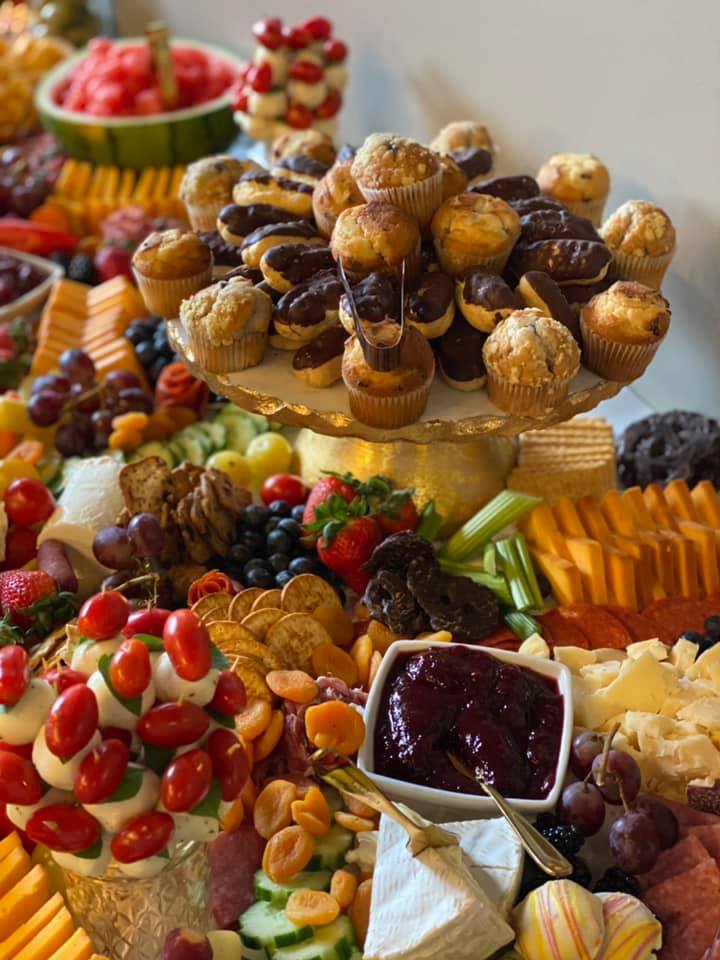 A grazing table has pastries with tongs, fruit, crackers, cheese, and more on a grazing table by Crafted and Carved. Photo from Crafted and Carved's Facebook page.