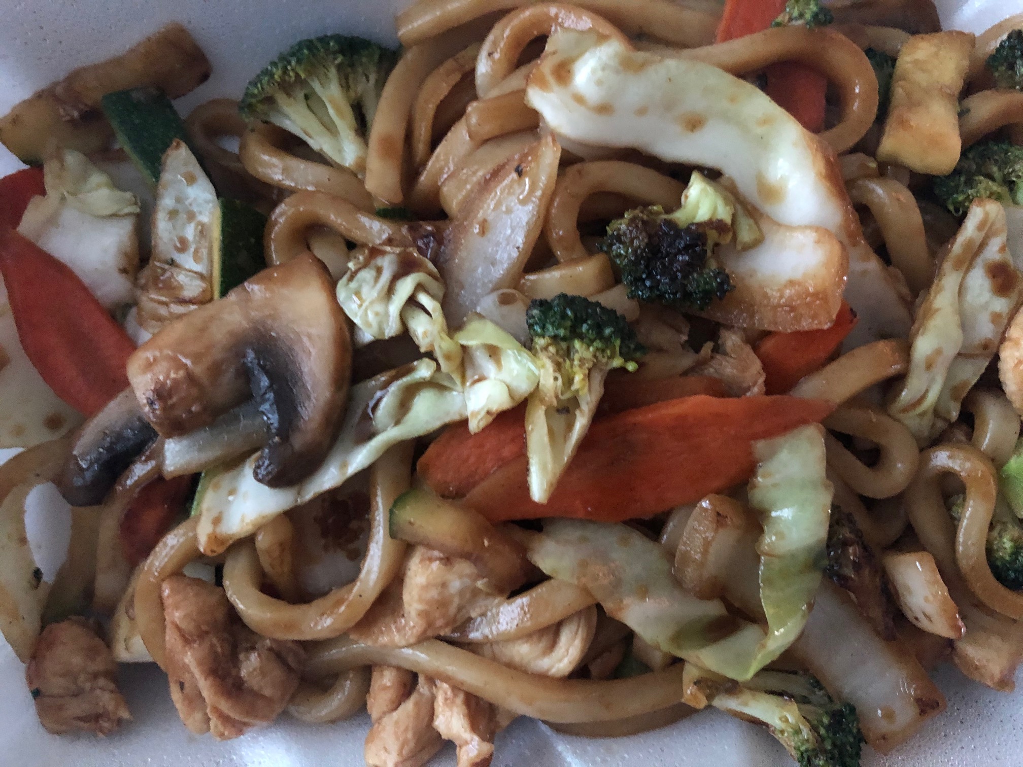A close up photo of the chicken yaki udon noodles from Sushi Kame featuring mushrooms, broccoli, and onions in between thick noodles. Photo by Alyssa Buckley.