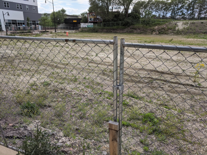 A vacant dirt lot with a chain link fence in the foreground. Photo by Tom Ackerman.