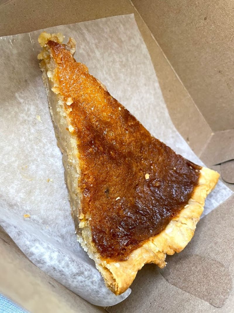 A slice of brown pie sits in a brown box on parchment paper. Photo by Remington Rock.