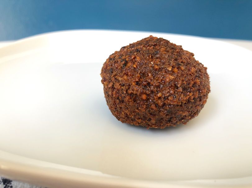 A single falafel ball sits on a white plate. Photo by Alyssa Buckley.
