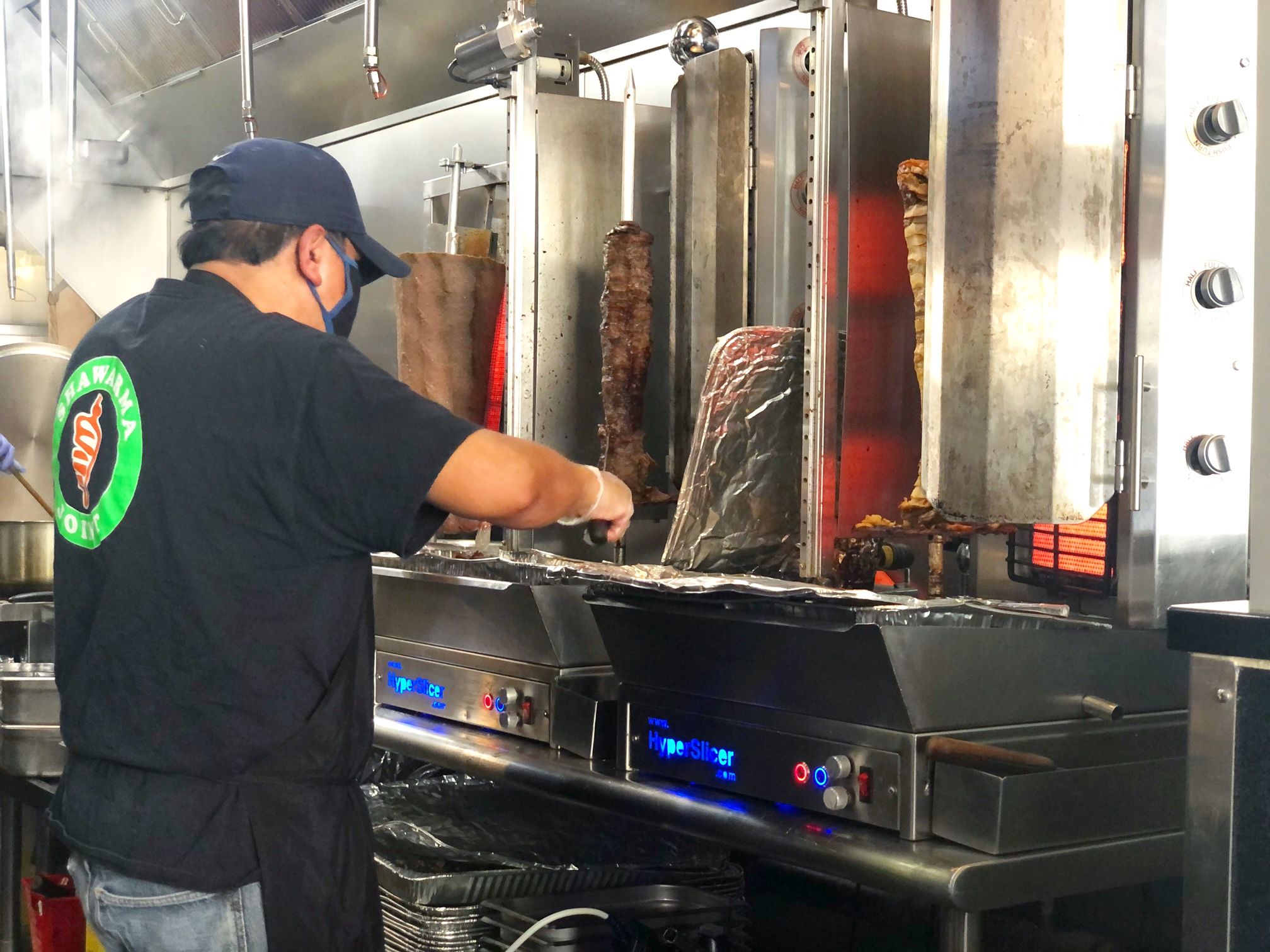 A staff person at Shawarma Joint slices lamb on a verticle rotisserie. Photo by Alyssa Buckley.