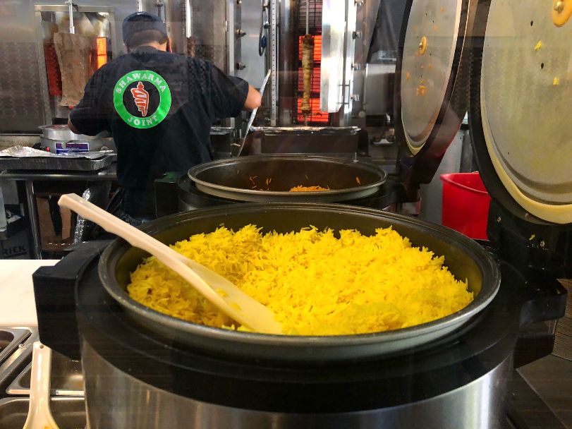At Shawarma Joint, there are two huge rice cookers, open. The one in front is filled to the top with yellow rice. Photo by Alyssa Buckley.