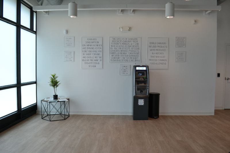Inside NuEra Champaign, the walls are white with a small table with a plant and a skinny ATM on the far wall. Photo by Alyssa Buckley.