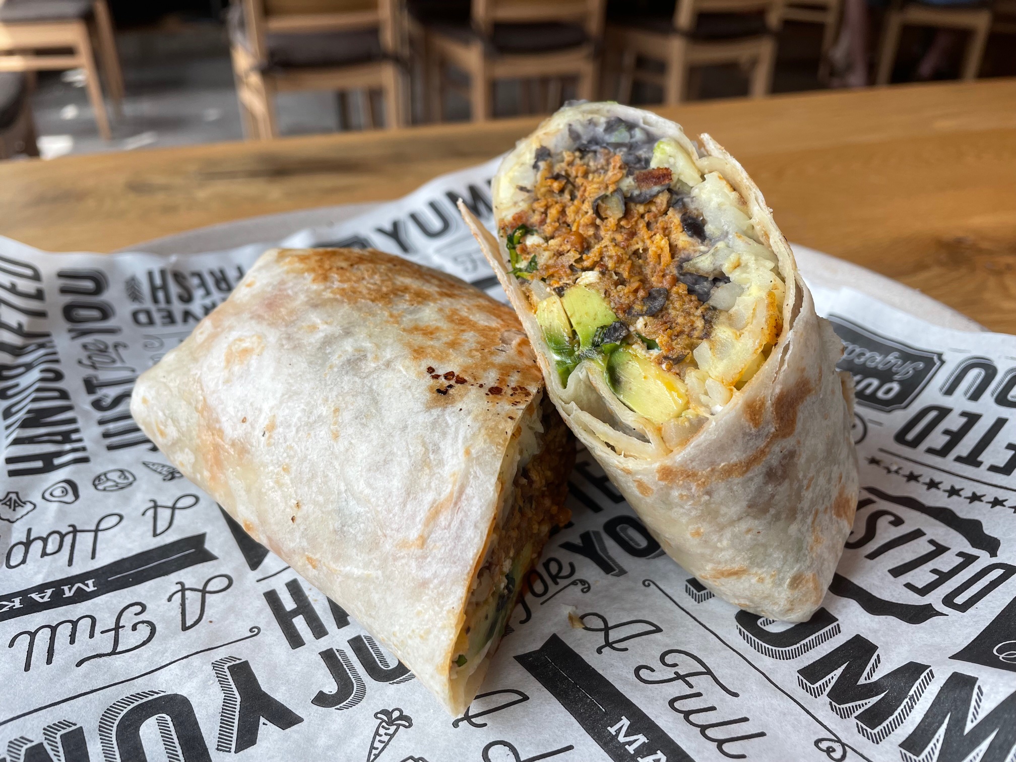 A chorizo burrito sliced in half and balanced on each other sits in a wordy parchment paper filled plate. Photo by Alyssa Buckley.