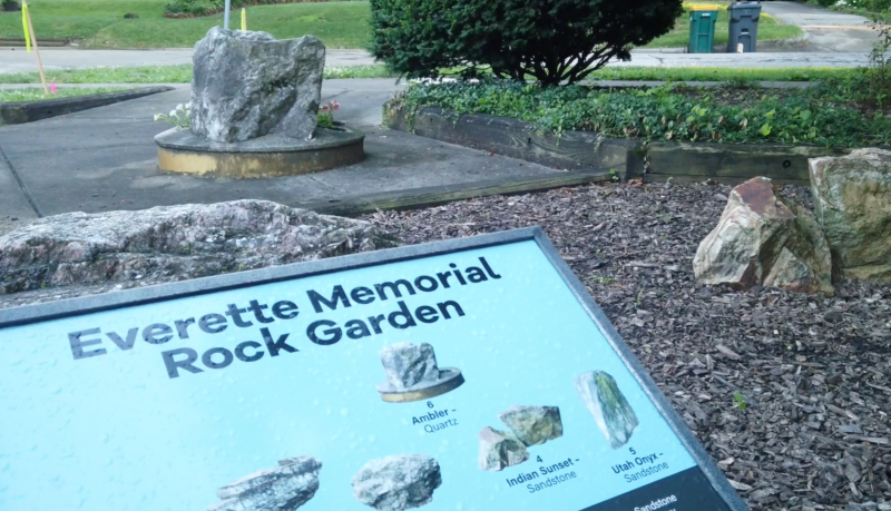 the sign for everette memorial garden next to massive rocks 