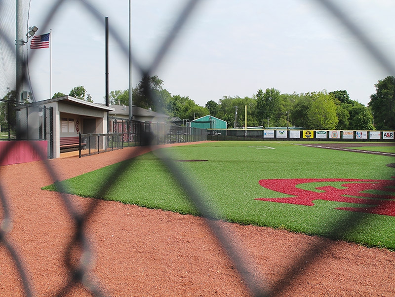 a high school baseball field viewed through a chain link fence