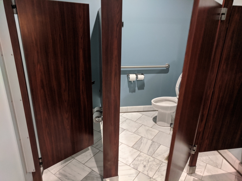 Two bathroom stalls with dark wood doors that are partially open. Photo by Tom Ackerman.