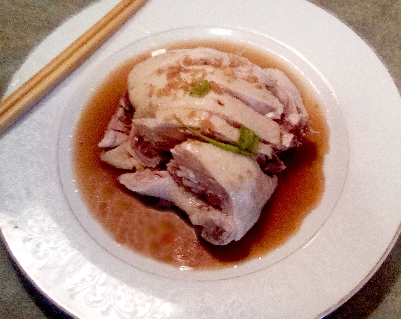 On a white plate, there is hacked chicken, light in color in a thin brown sauce. Photo by Paul Young.