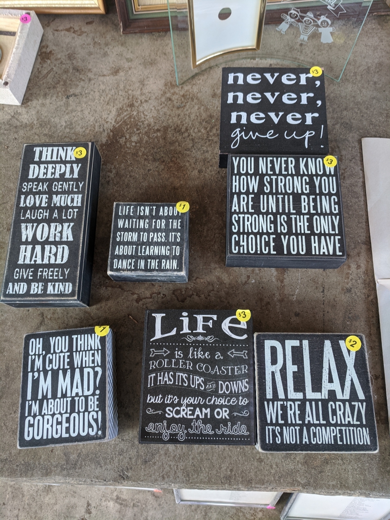 A collection of wood block signs with black backgrounds and inspirational phrases in white lettering. Photo by Tom Ackerman. 