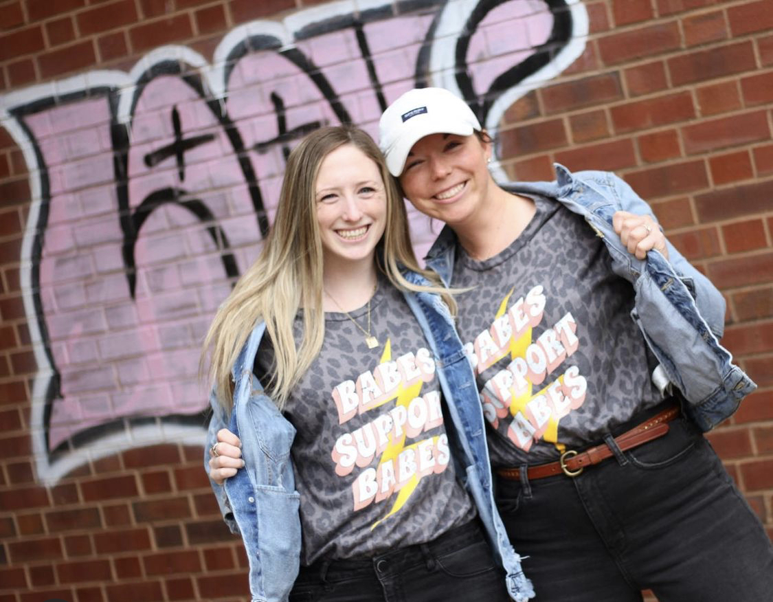 Cassie and Emma, the owners of Butter Babes, wear matching gray t-shirts that read 