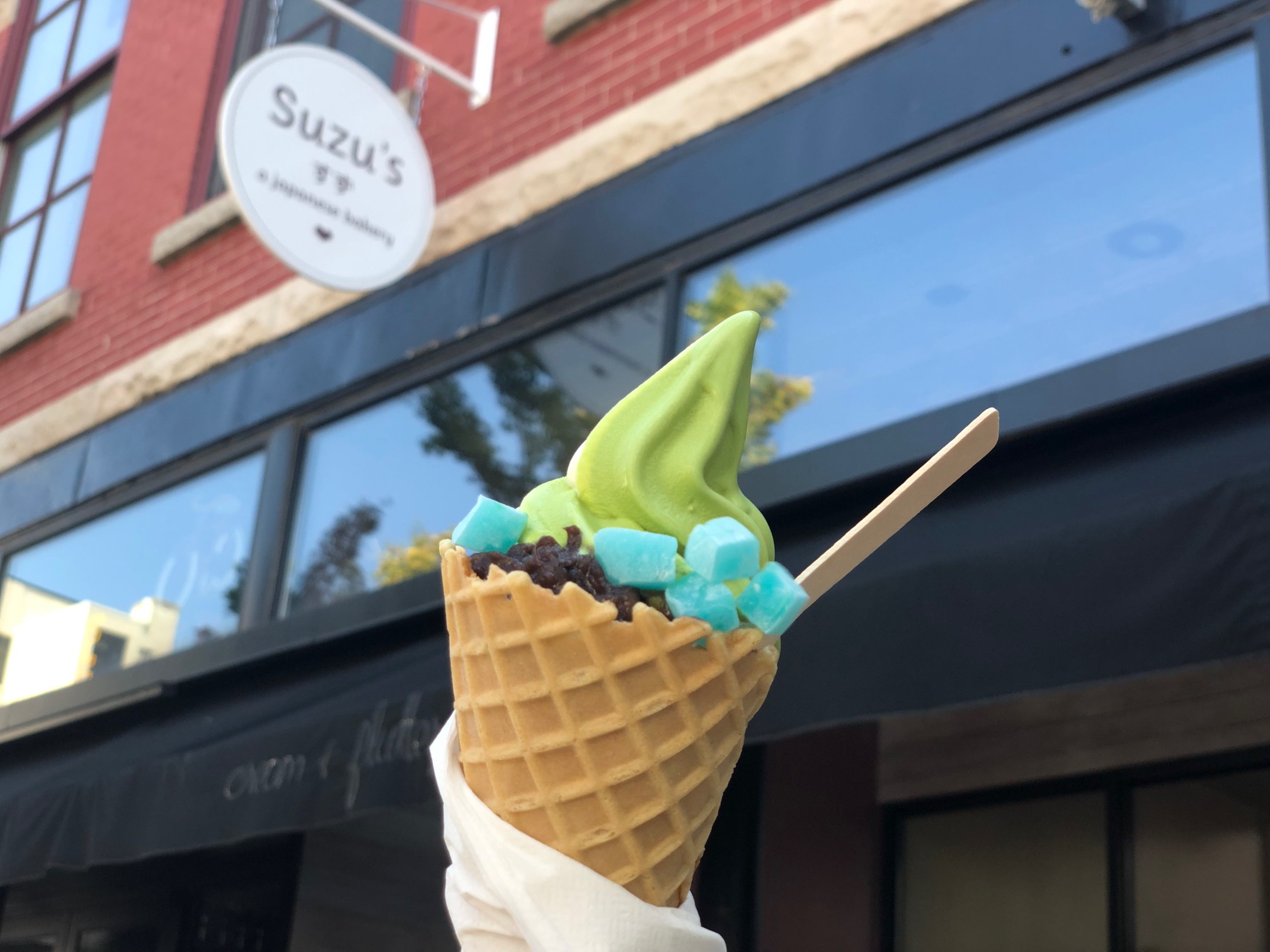 In front of Suzu's Bakery in Downtown Champaign, there is a cone of matcha green ice cream with red bean paste and blue mochi toppings. Photo by Alyssa Buckley. 