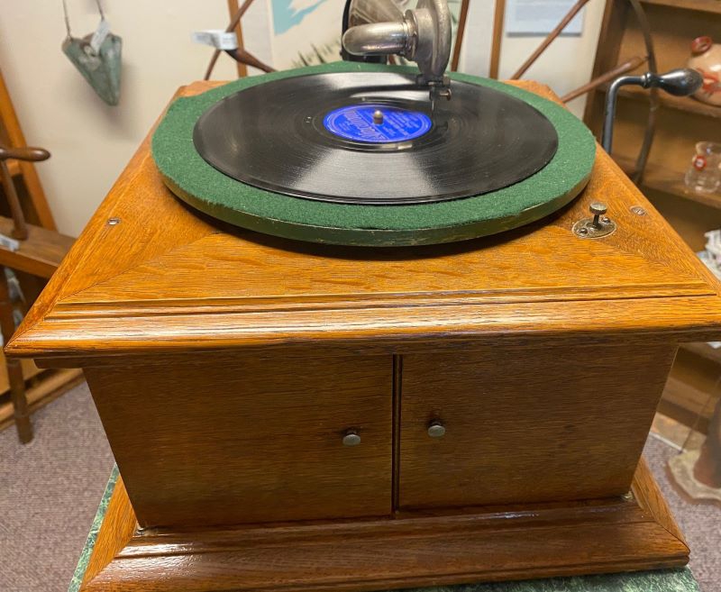 A turntable sits on a light wood square base. There is a record on the turntable. Photo by Julie McClure.