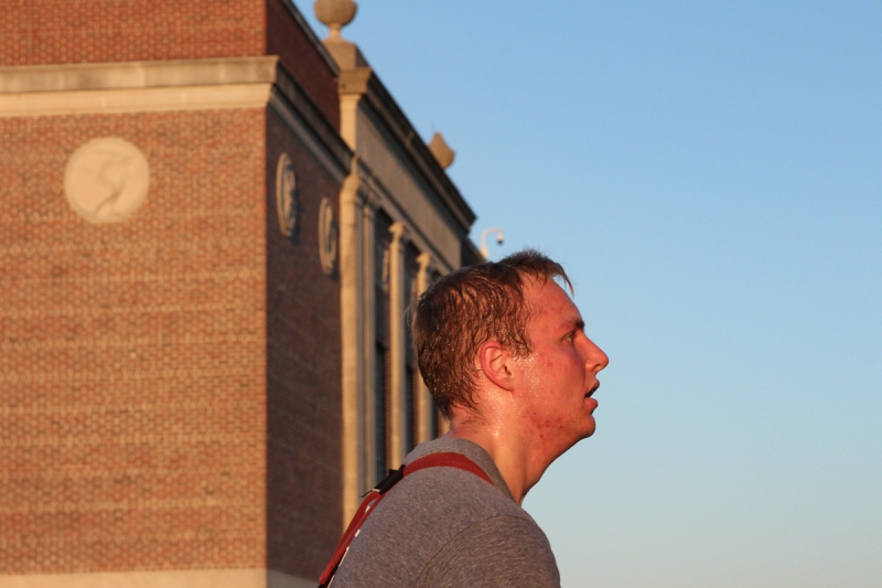 Tom Compere, a student at U of I and volunteer firefighter looks up into the morning sun as he completes the stair climb. He wears a grey shirt and red suspenders. His head is drenched in sweat and his hair is soaked. Photo by Justin Malone.