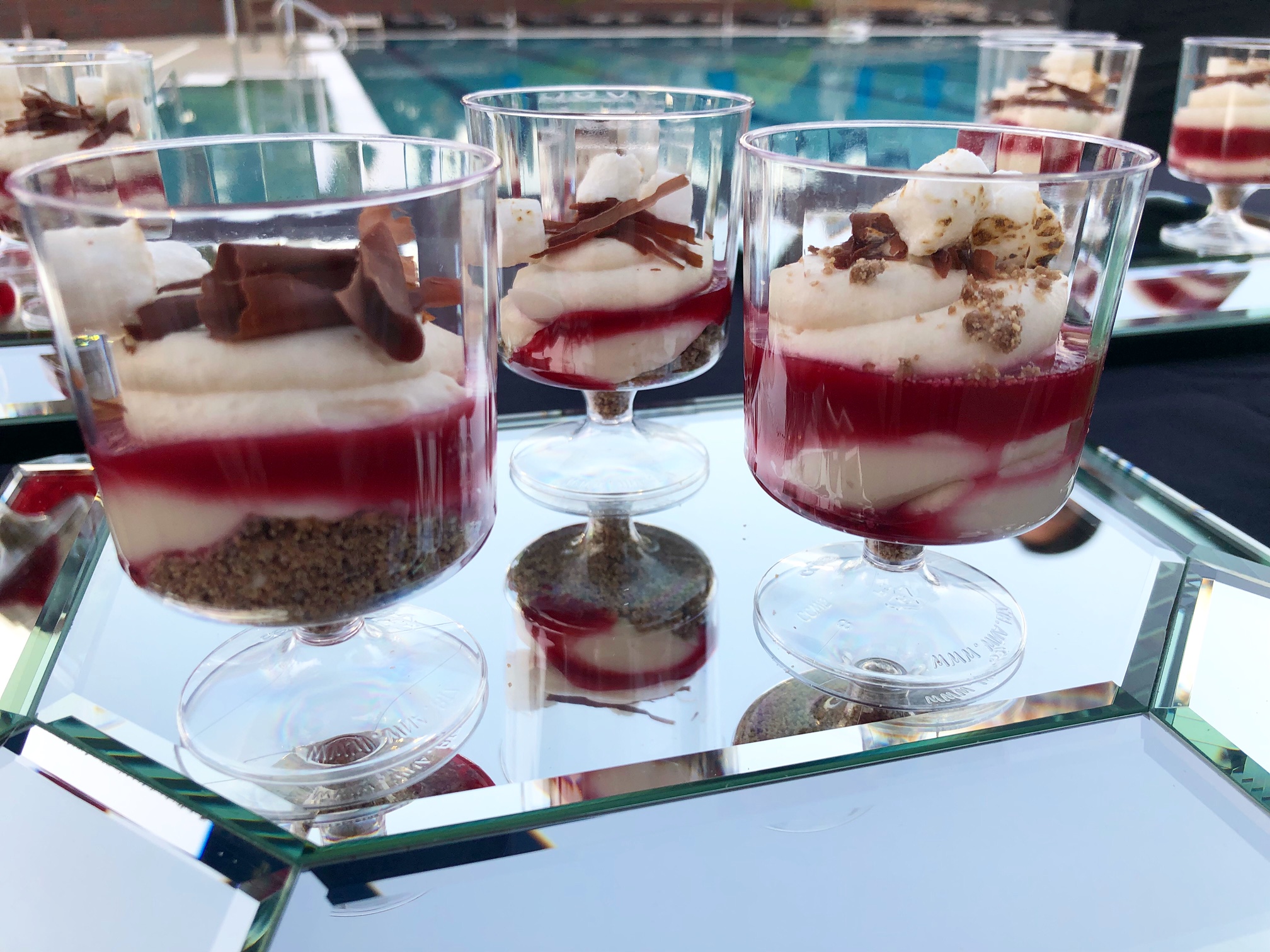 On a hexagon mirror, three strawberry s'more parfaits sit in stemmed glasses. Photo by Alyssa Buckley.