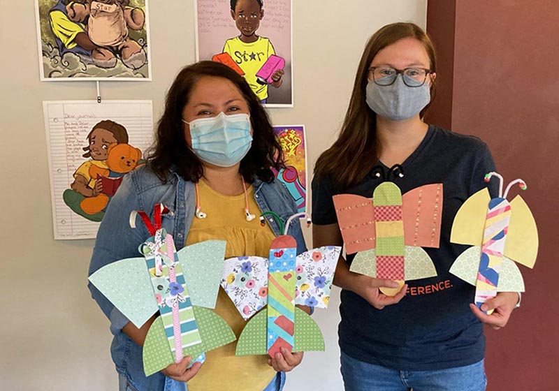 Photo of two young people holding handmade paper butterflies. Photo from the University YMCA New American Welcome Center.