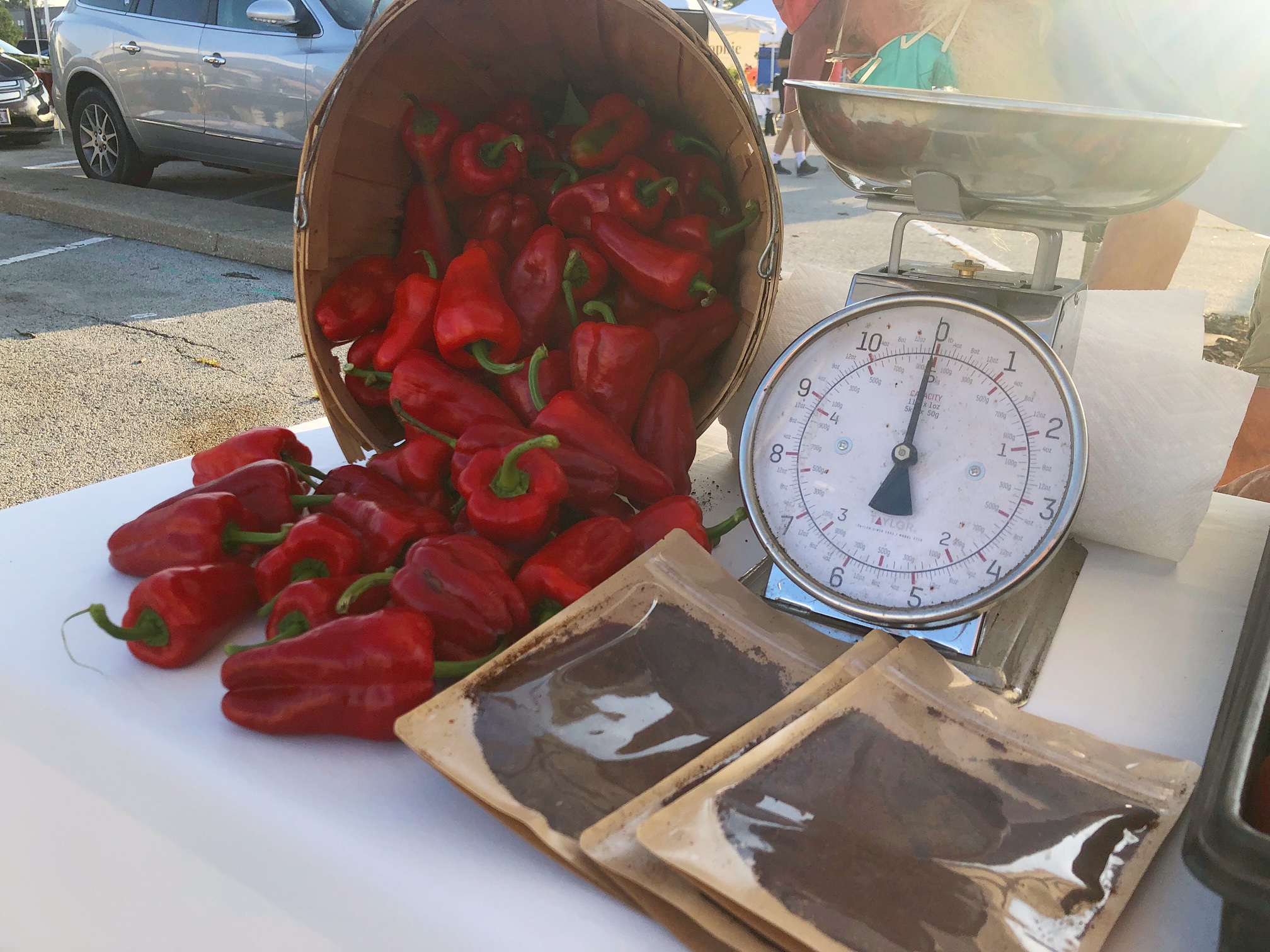 On a white tablecloth, there is an overturned basket of paprika peppers beside clear bags of paprika spice in front of an old fashioned silver scale. Photo by Alyssa Buckley.