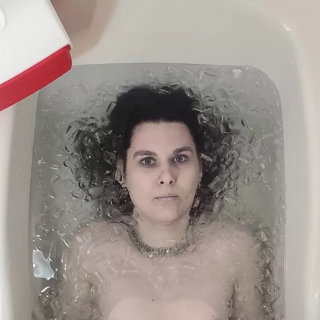 Image of artist Extremely Mundane looking into the camera while in an ice bath. 