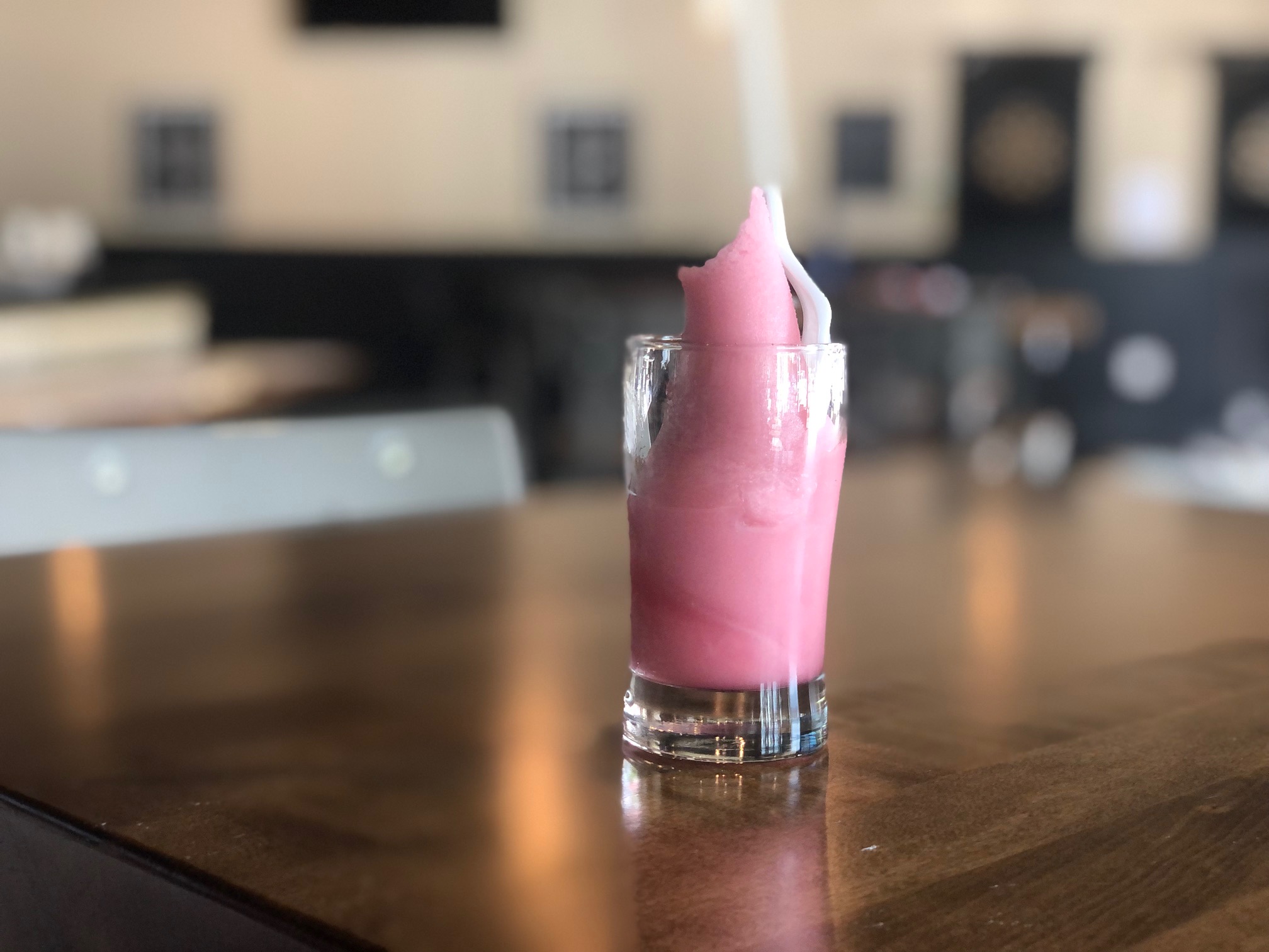 On a wooden table at Collective Pour, a small glass cup holds pink soft serve. Photo by Alyssa Buckley.