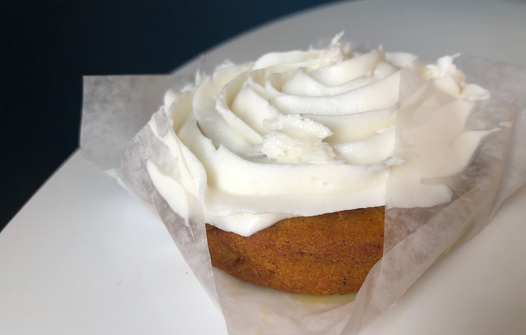 In a piece of white parchment paper, there is a pumpkin spicebush cake with cream cheese frosting. Photo by Alyssa Buckley.