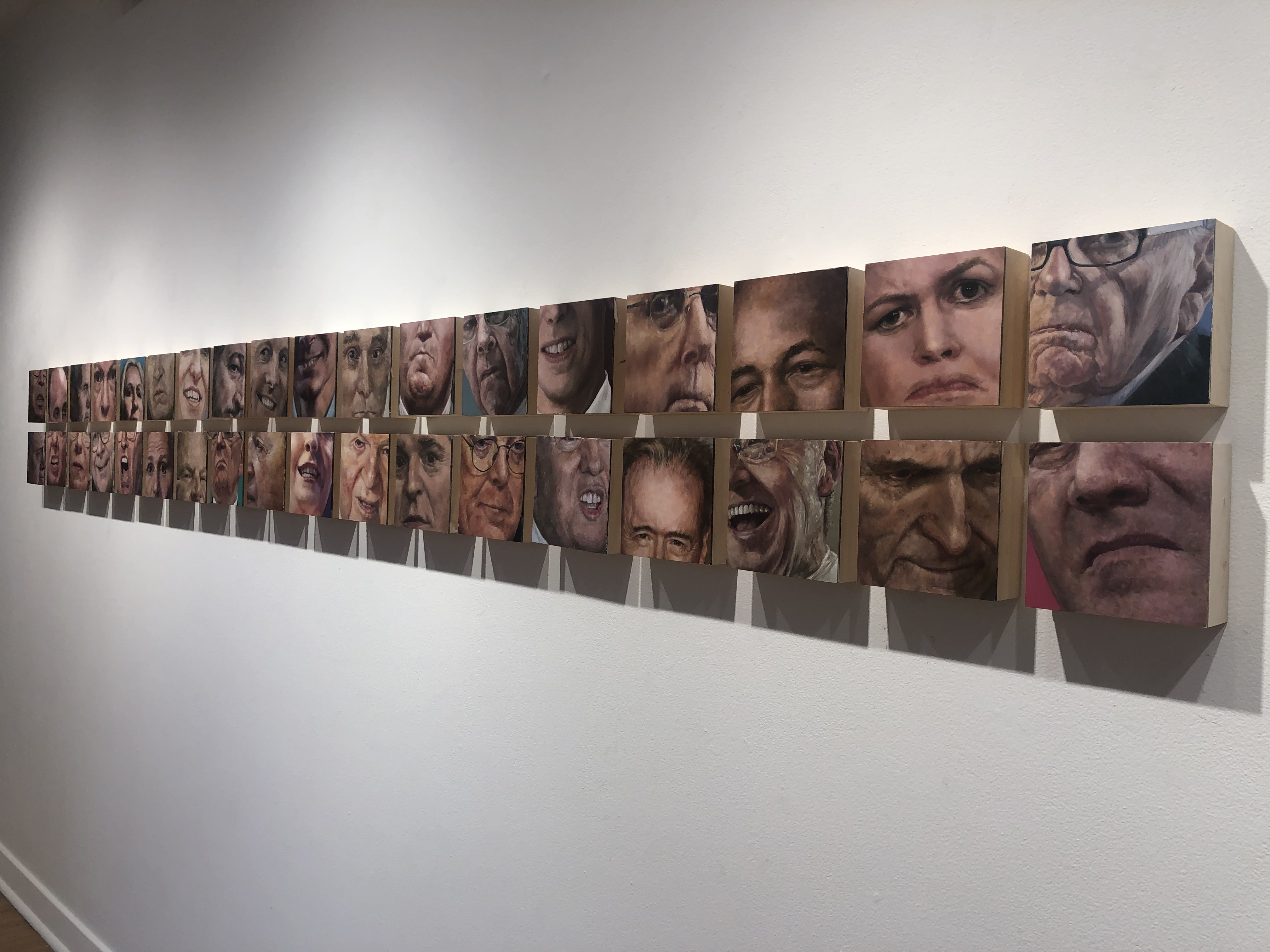Two rows of small oil on wooden block paintings of over thirty faces of famous politicians and political donors, with a tight emphasis on the facial skin and skin tones of each person featured. Skin in the Game, 2021. Photo by Amy Penne. 