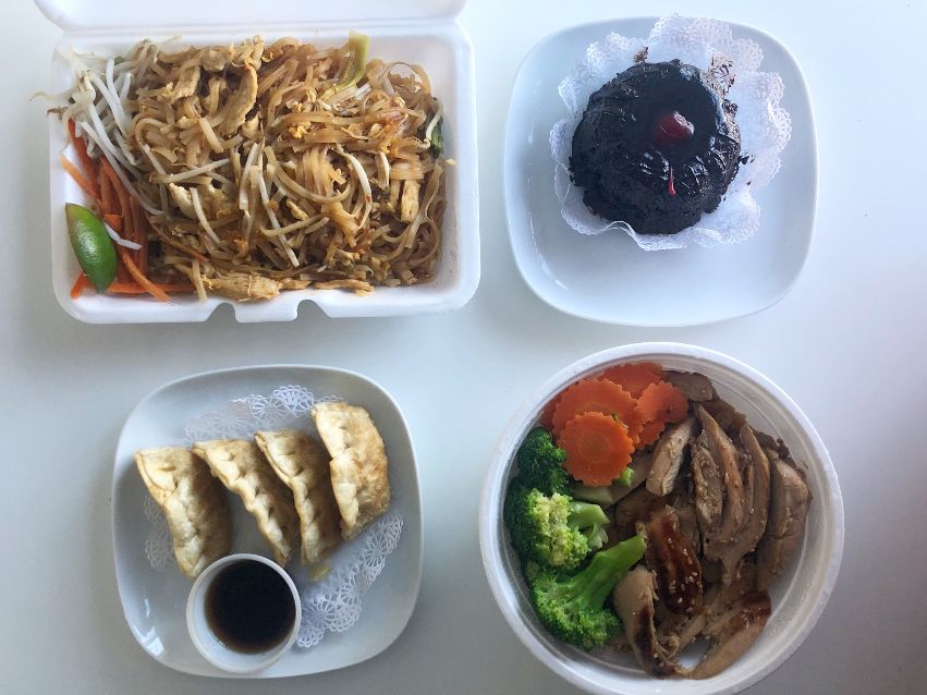 An overhead photo shows pad Thai, dumplings, chicken teriyaki, and a chocolate lava cake. Photo by Alyssa Buckley.