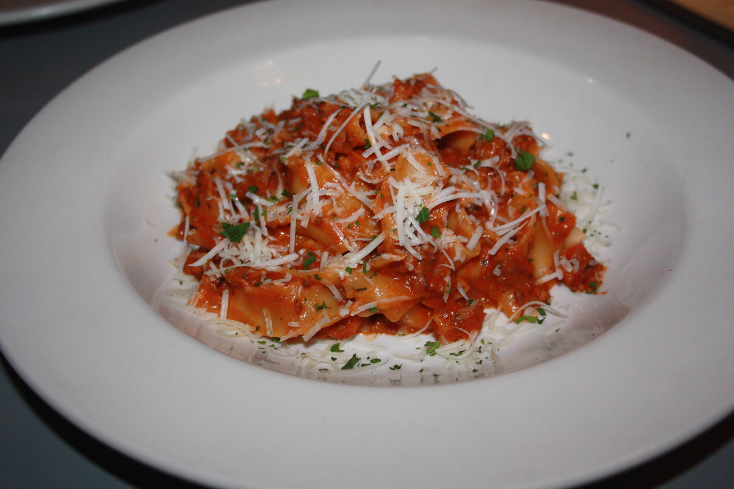 On a white plate, a pasta dish with red sauce is topped with grated parmesan. Photo by Rebecca Wells.