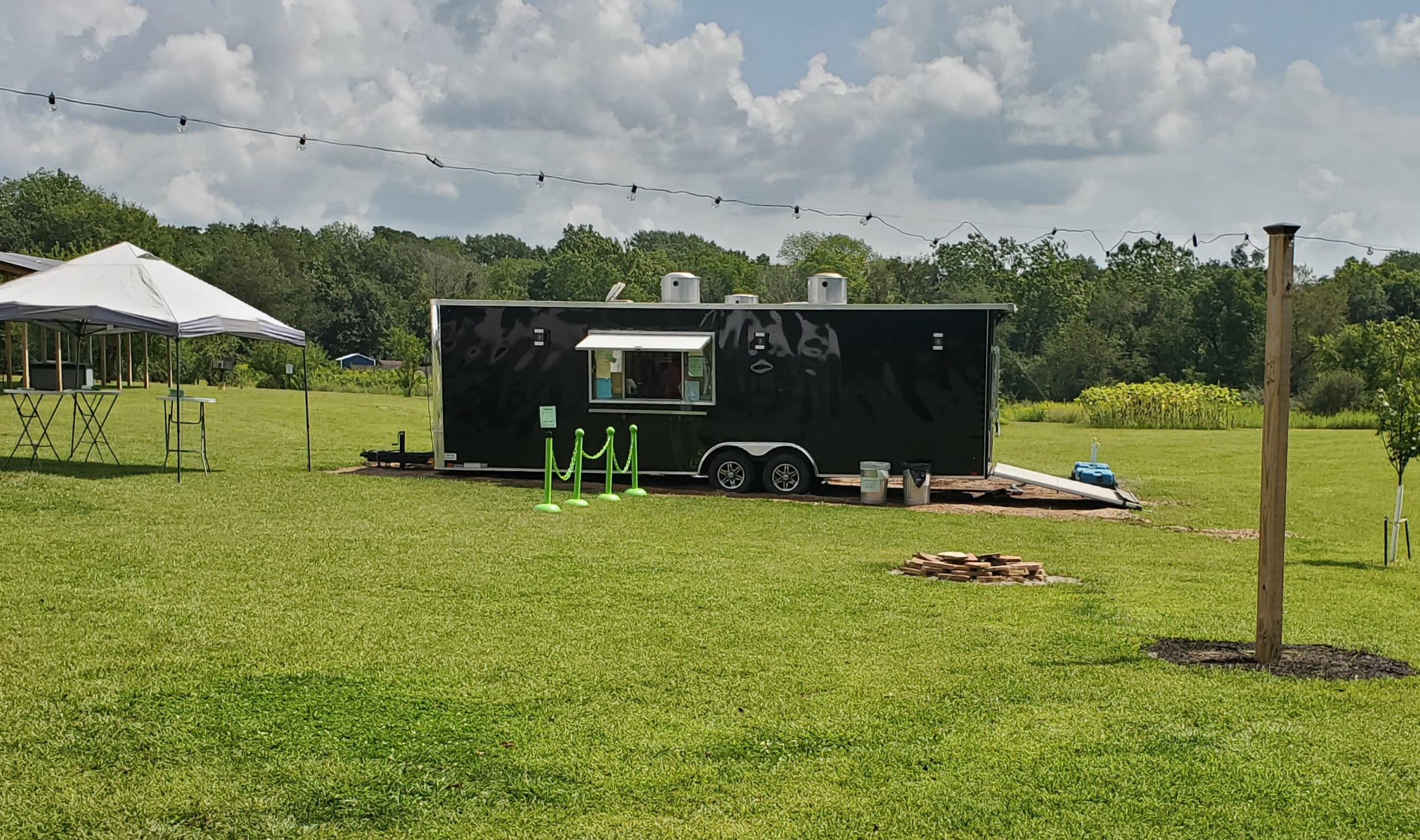 A black food truck is parked in the grass on a sunny day. Photo by Carl Busch.