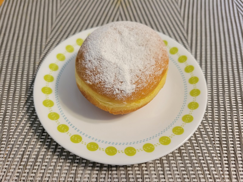 A Bombolone covered in powered sugar on a small plate. Photo by Matthew Macomber.