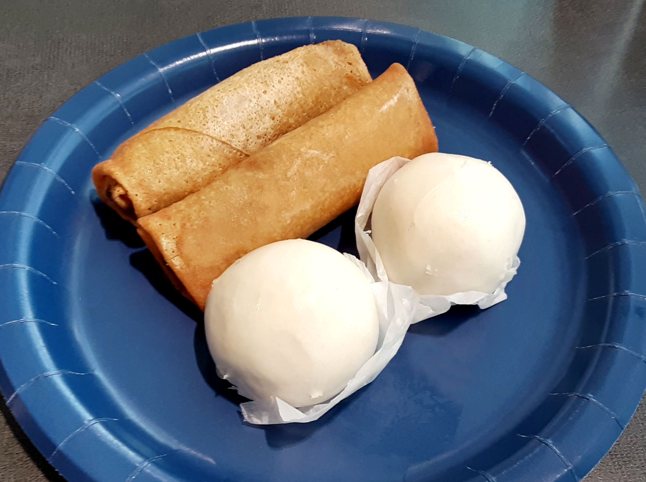 On a blue plate, there are two fried egg rolls and two steamed buns. Photo by Paul Young.