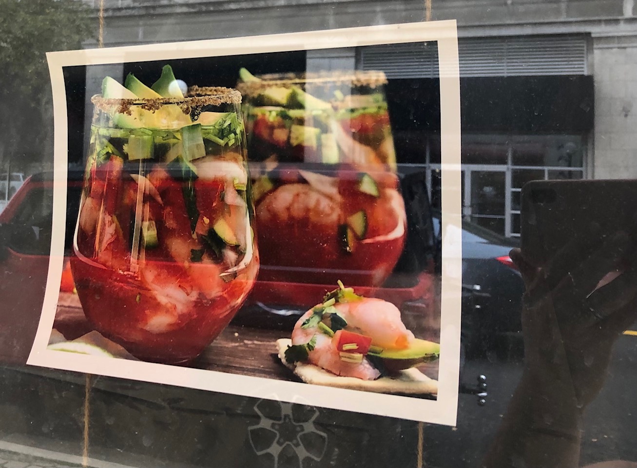 On a color print out of a photo, there are two large wine glasses full of a red liquid with seafood and cucumber. Photo by Alyssa Buckley.
