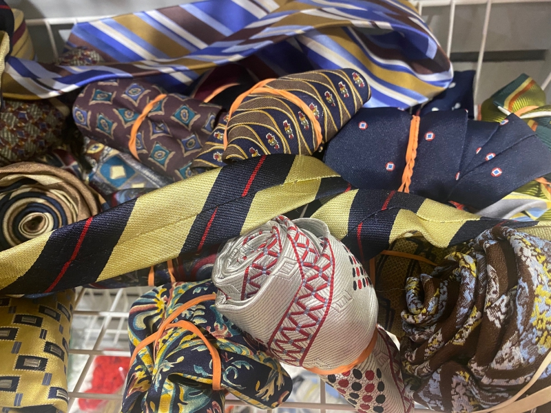 A collection of patterned necktties. Many are rolled up, a couple of them are draped across the container. Photo by Julie McClure.