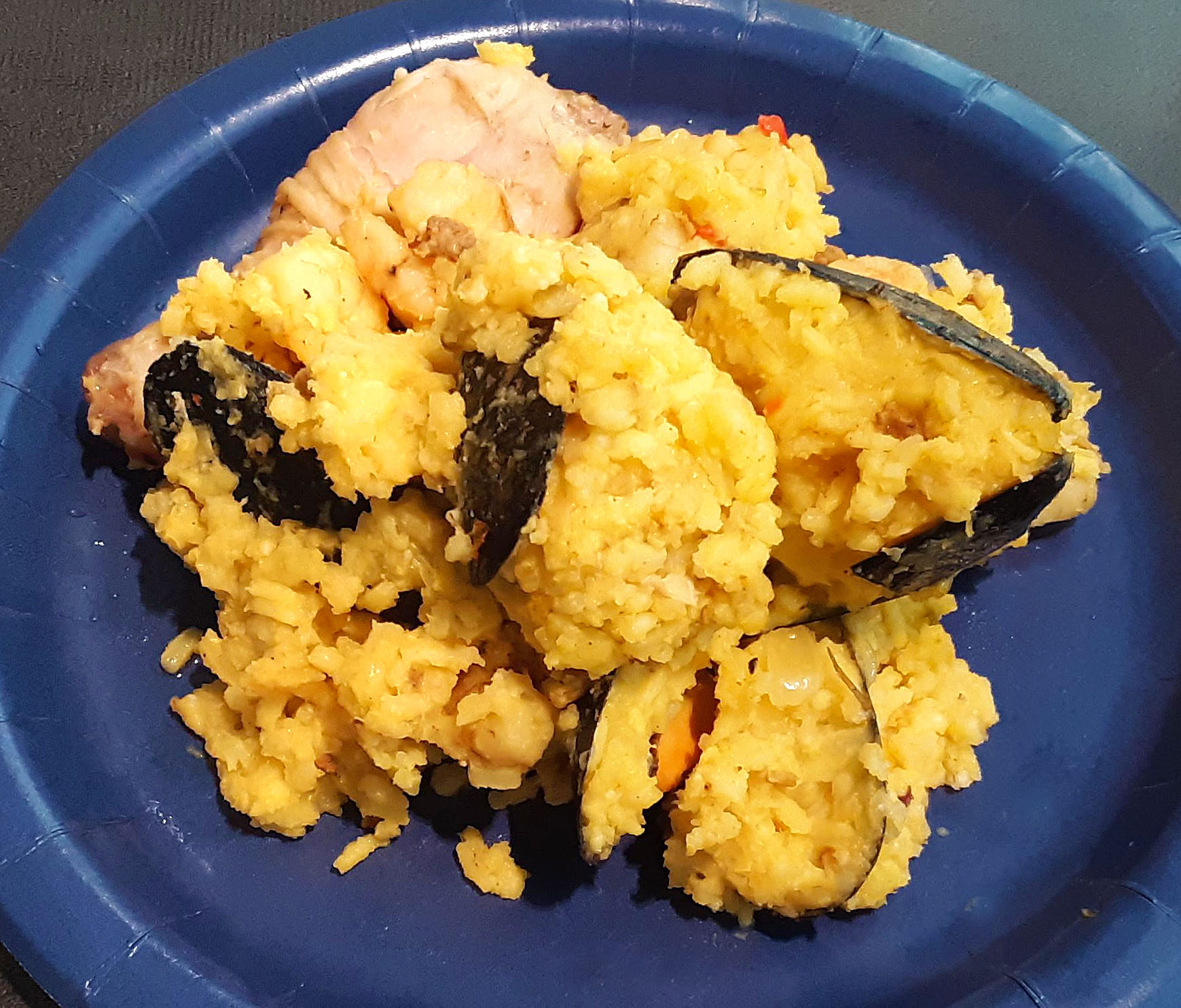On a blue paper plate, there was a scoop of paella with lots of open mussels. Photo by Paul Young.