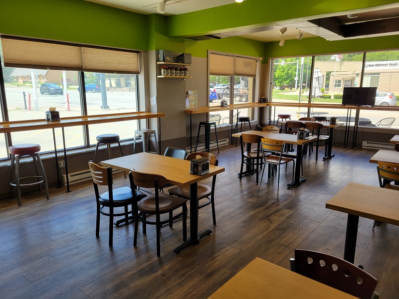 Seating inside of Pekara with four chairs to a table and higher single stools by windows. Photo by Matthew Macomber.