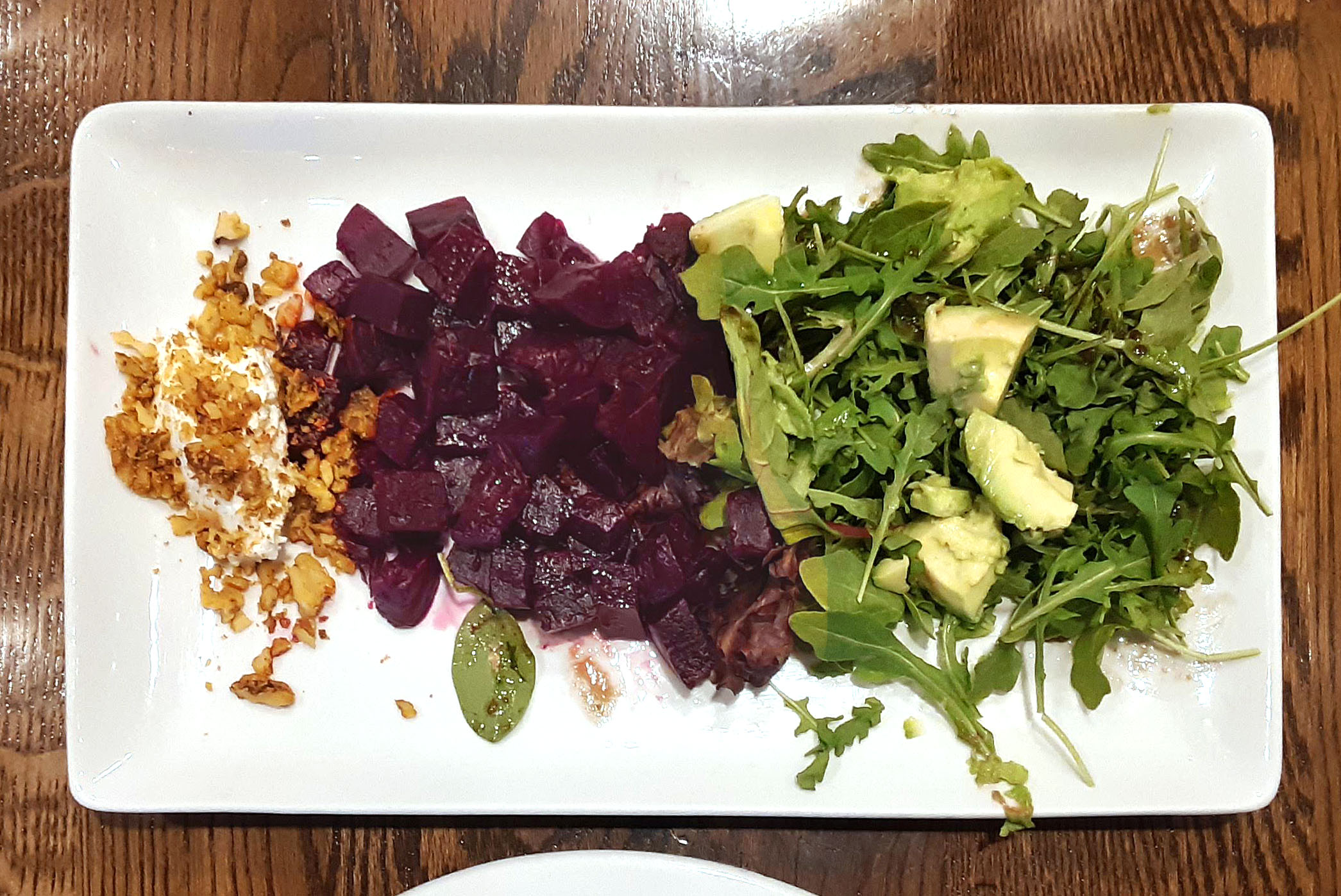 On a rectangular white plate, there are three apps: beets, avocado, and greens. Photo by Paul Young.